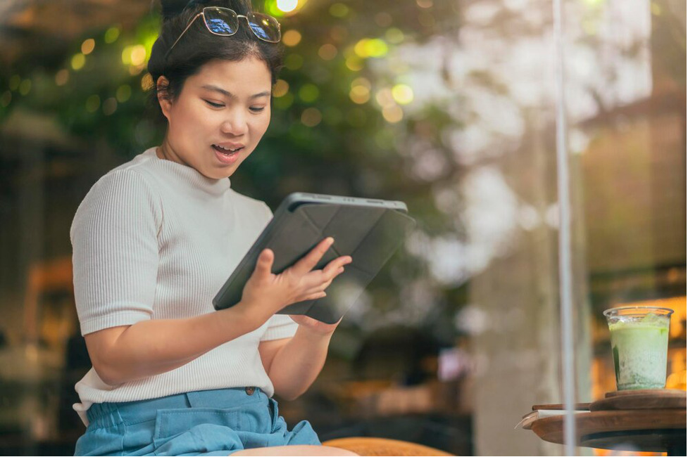 Seorang wanita sedang menggunakan tablet untuk mengakses platform baca buku online gratis.