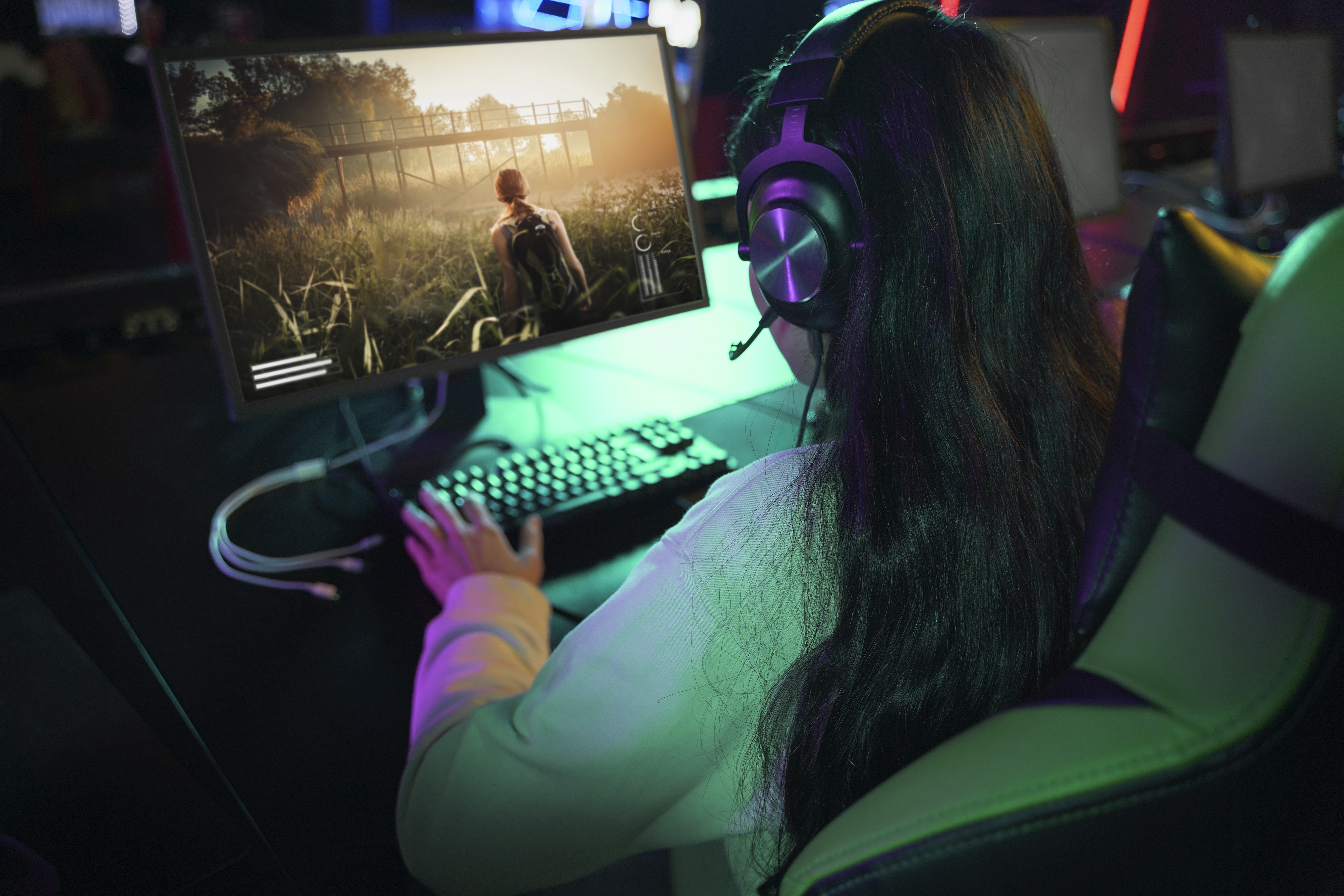 High-angle view of a woman playing a video game on her computer, with smooth, lag-free gameplay supported by a strong connection (WiFi terbaik).