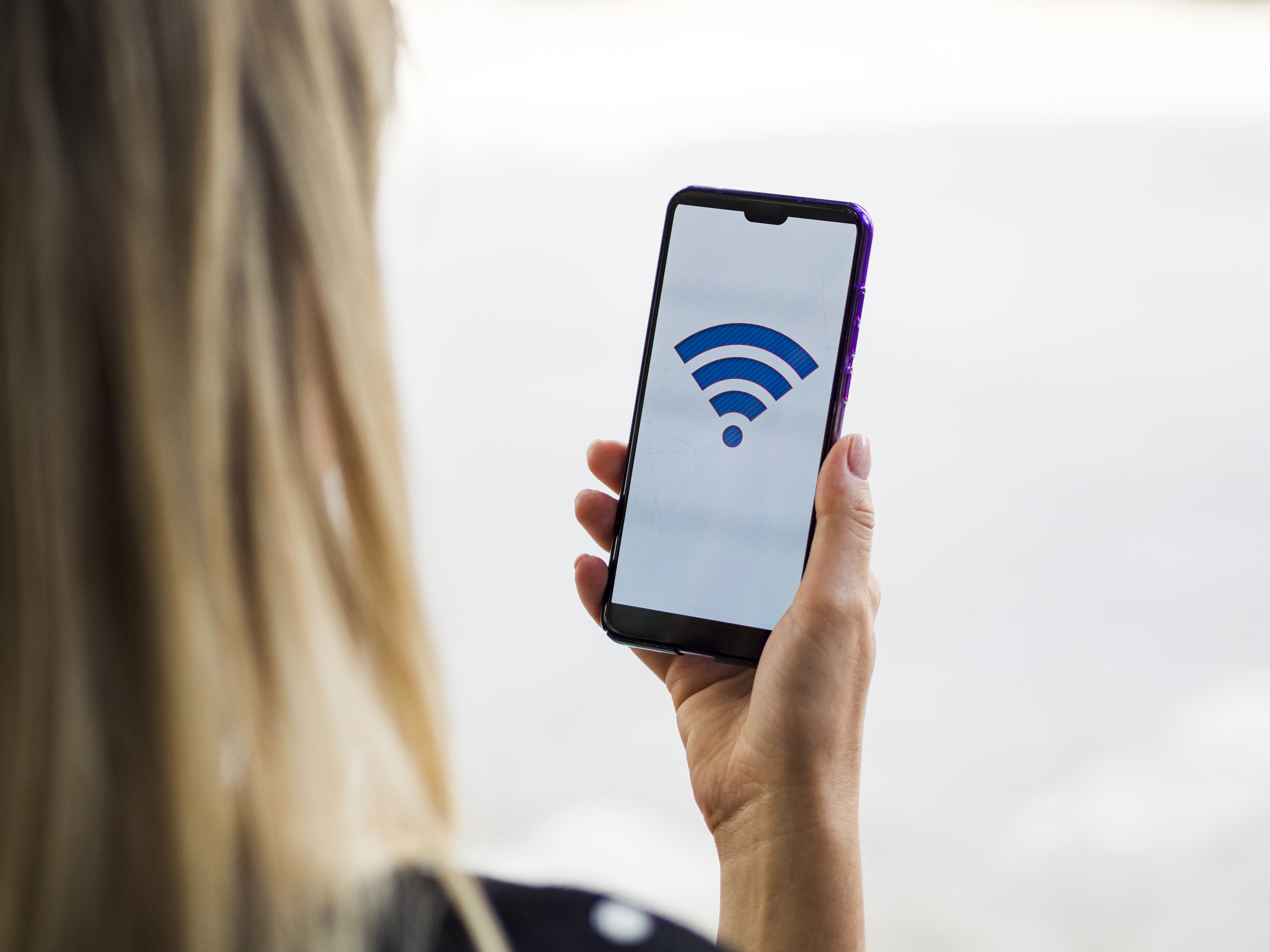 Close-up of a woman checking her phone, representing the search for the nearest WiFi connection using a WiFi map (WiFi map terdekat).