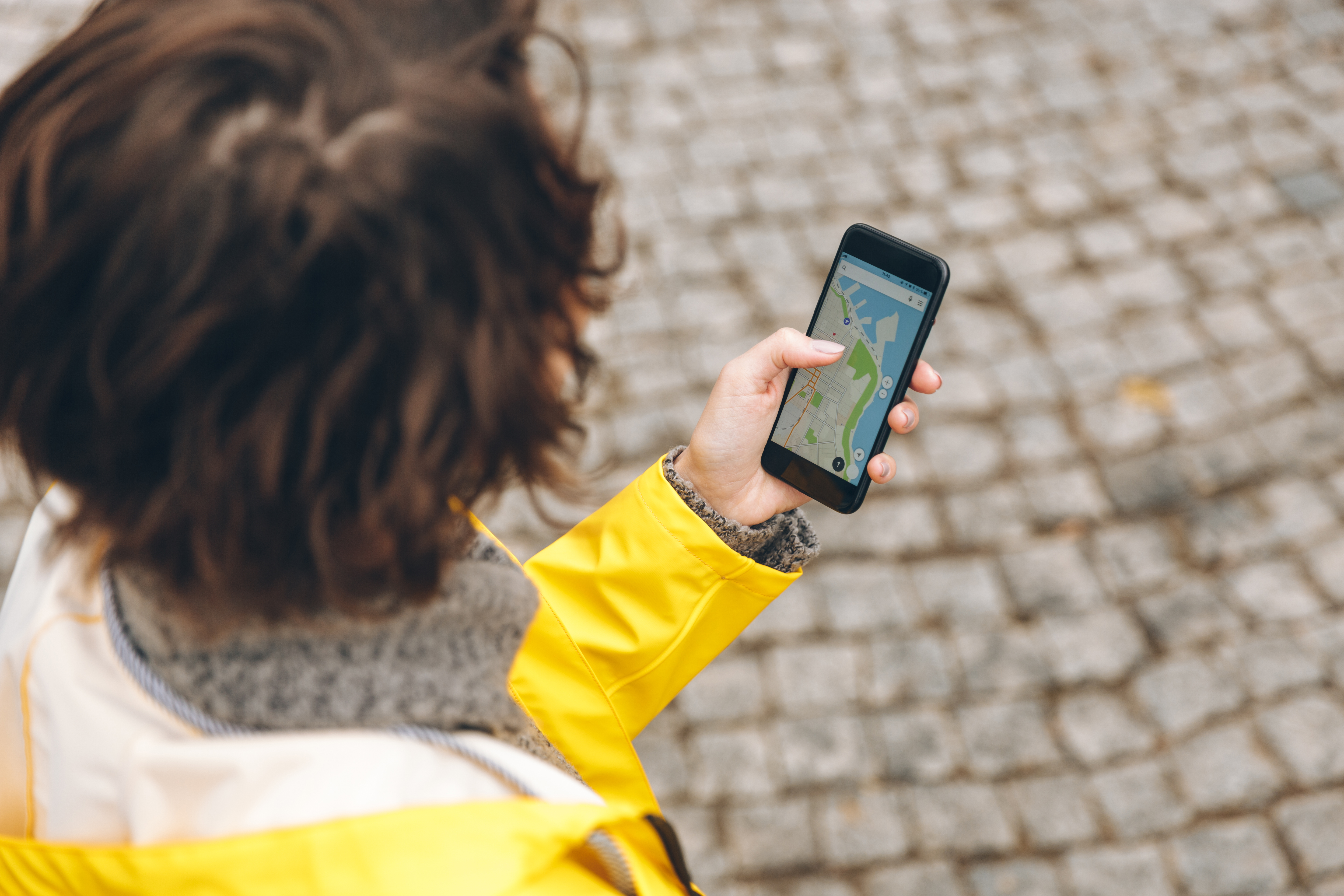 Top-down view of a confused brunette woman standing alone in an unfamiliar location, illustrating the concept of tracking a lost phone (cara melacak HP hilang).