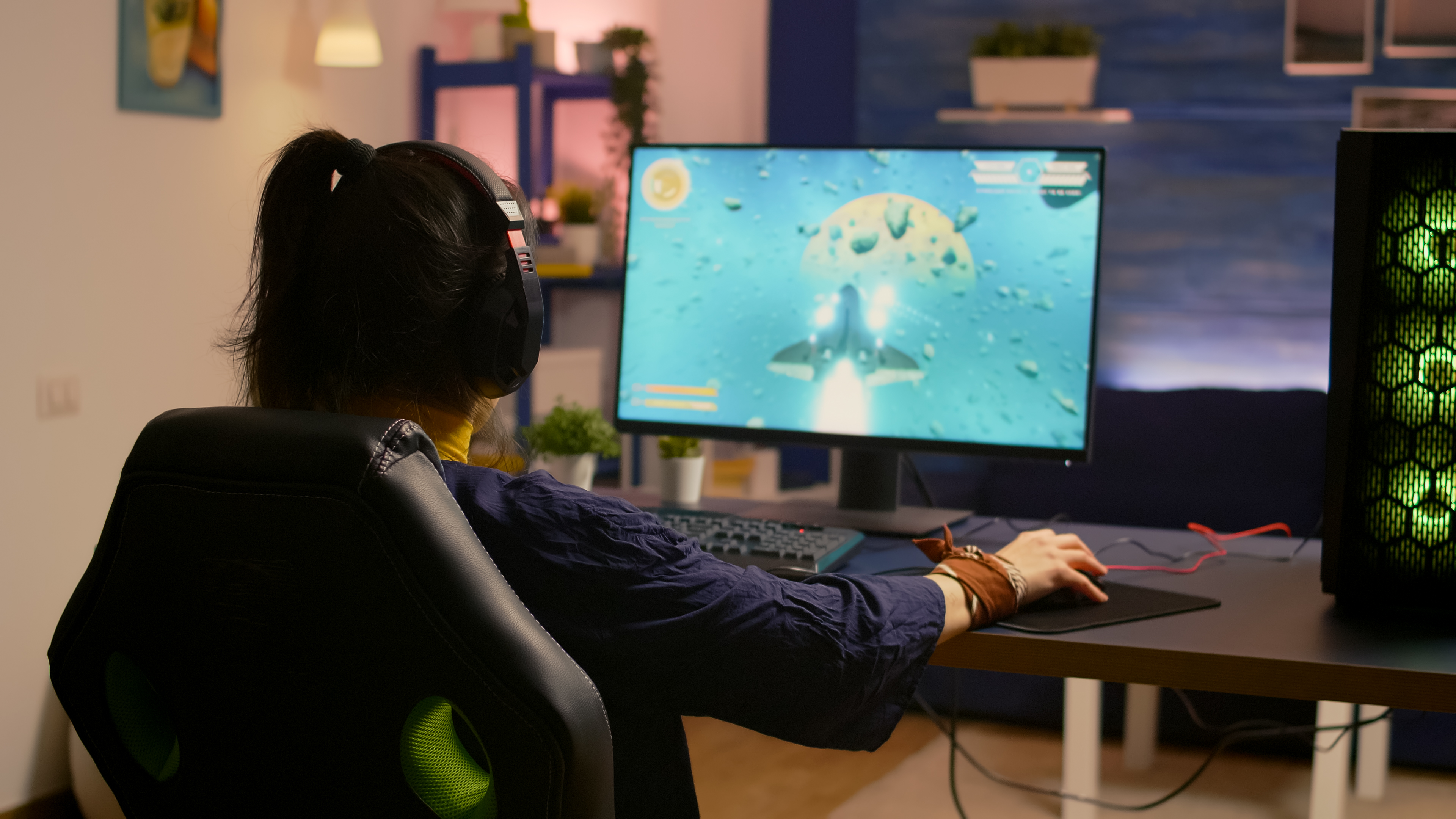 Winner gamer sitting on gaming chair at desk and playing space shooter video games with RGB keyboard and mouse. Player streaming online video games for esport tournament in room with neon lights