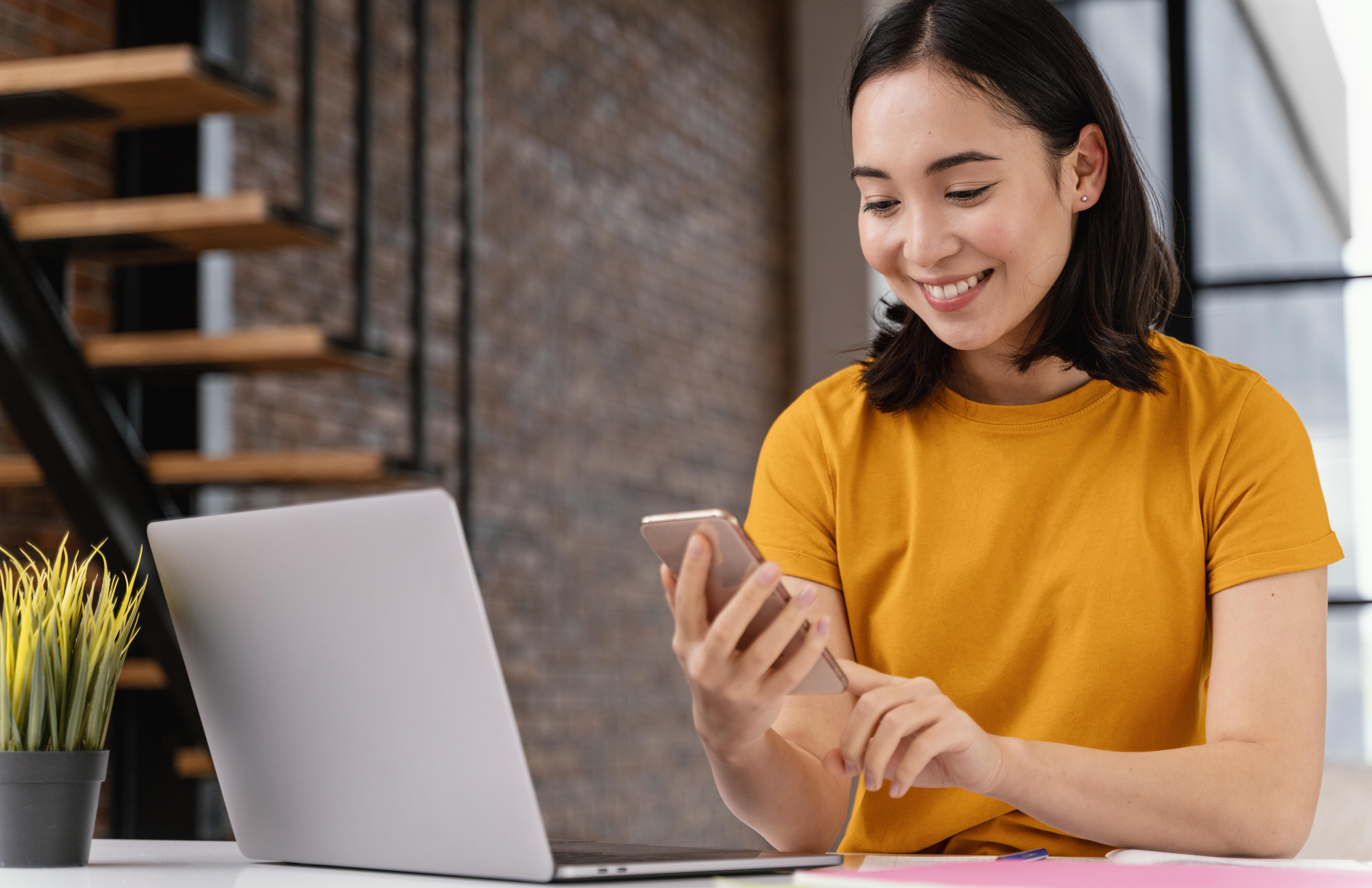 Young woman using phone and laptop for hoe to secure concert tickets online (cara war tiket konser).