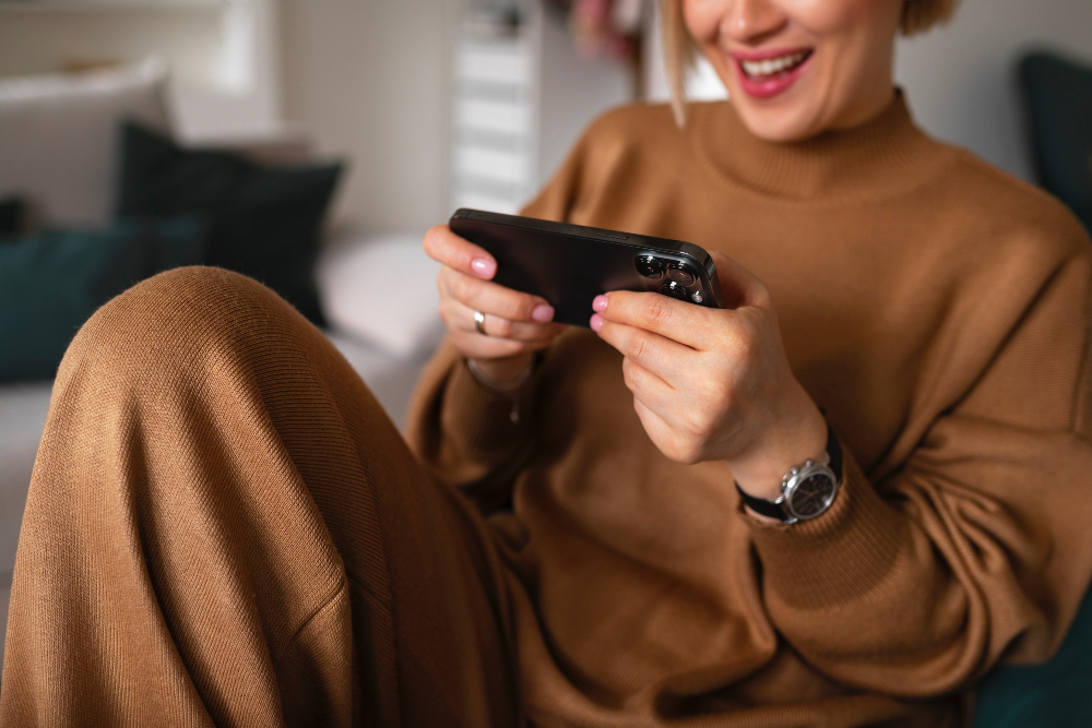 High-angle view of a young woman relaxing while using her smartphone during a break, as an illustration on how to fix a slow phone (cara agar HP tidak lemot).