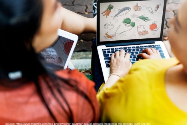 Woman and young girl using a laptop together, illustrating the Shopify vs WordPress comparison.