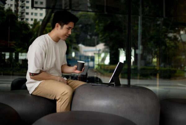 Asian professional working on a tablet with a keyboard outdoors, representing a flexible digital lifestyle.